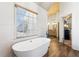 Bright bathroom with a modern tub, wood flooring, and access to the vanity at 2952 Perimeter Cir, Buford, GA 30519