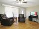 Cozy living room featuring hardwood floors, a ceiling fan, and two comfortable leather chairs near the window at 2870 Whiteview Nw Dr, Acworth, GA 30101
