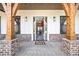Inviting front porch with brick columns, wood beams, and a glimpse into the home's foyer at 8710 Little Mill Rd, Cumming, GA 30041