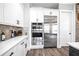 Bright kitchen with stainless steel refrigerator, double ovens, white cabinets, and dark wood floors at 8710 Little Mill Rd, Cumming, GA 30041