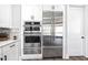 Bright kitchen with stainless steel refrigerator, double ovens, and white cabinets at 8710 Little Mill Rd, Cumming, GA 30041