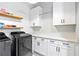 Well-organized laundry room with stylish appliances, white cabinetry, quartz counters, and floating wood shelves at 8710 Little Mill Rd, Cumming, GA 30041