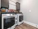 Laundry room featuring modern washer and dryer units, dark cabinets, a hanging rack, and wood-look floors at 8710 Little Mill Rd, Cumming, GA 30041