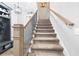 Carpeted stairway with wooden handrail and black iron balusters leads to the upper level of this home at 8710 Little Mill Rd, Cumming, GA 30041