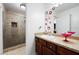 Well-lit bathroom with a glass enclosed shower, brown vanity with decorative mirror and accessories at 1227 Castle Point Sw Ct, Conyers, GA 30094