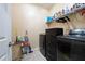 Functional laundry room with front-loading washer/dryer, storage unit, shelving, and ample space for laundry tasks at 1227 Castle Point Sw Ct, Conyers, GA 30094