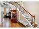 Elegant staircase with wooden banister, hardwood floors, and display cabinet at 1227 Castle Point Sw Ct, Conyers, GA 30094