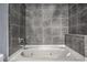 Close-up shot of a luxurious white bathtub with jacuzzi jets and gray tiled walls in the bathroom at 275 13Th St # Apt 509, Atlanta, GA 30309