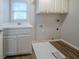 Convenient laundry room with sink, white cabinets, and laminate floors at 4570 Thicket Trl, Snellville, GA 30039