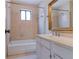Bright bathroom featuring a vanity with marble countertop, framed mirror, and tub with tiled walls and window at 2 Westchester Sq, Decatur, GA 30030