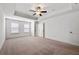 A bright bedroom featuring a tray ceiling, ceiling fan, neutral carpet, and two closets at 2230 Mulsanne Dr, Lithonia, GA 30058
