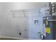 This is an installed, wall-mounted water heater next to water hookups and a wire rack for storage at 9090 Dorsey Rd, Riverdale, GA 30274
