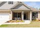 Charming brick home with a welcoming front porch, complemented by a table and chairs, and beautiful landscaping at 7995 Brewton Creek Dr, Cumming, GA 30028