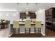 The kitchen is staged with bar stools, pendant lighting, dark cabinets, stainless appliances, and a functional island at 7995 Brewton Creek Dr, Cumming, GA 30028