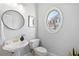 Powder room featuring an oval window, pedestal sink, round mirror, and grey paint at 2456 Manor Walk, Decatur, GA 30030