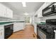 A kitchen featuring white cabinets, a microwave, and a black gas range oven at 11853 Harbour Town Pkwy, Fayetteville, GA 30215