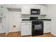 A kitchen featuring white cabinets, a microwave, and a black gas range oven at 11853 Harbour Town Pkwy, Fayetteville, GA 30215