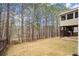 Backyard view featuring a well-maintained lawn, tall trees, and a raised deck with screened porch at 3680 Falling Leaf Ln, Cumming, GA 30041