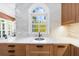 Bright kitchen area with undermount sink, quartz countertops, custom wood cabinets, and a window overlooking greenery at 135 Newcastle Ct, Roswell, GA 30076