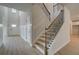 Elegant foyer featuring a staircase with wrought iron spindles, wood-look flooring, and wainscoting details at 112 Felicity Pike, Locust Grove, GA 30248