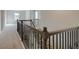 A hallway with dark metal and wood handrail overlooks stairs with carpet at 112 Felicity Pike, Locust Grove, GA 30248