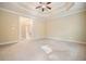 Spacious main bedroom featuring a tray ceiling, ceiling fan, carpet, and bathroom access at 620 Willow Haven Way, Suwanee, GA 30024