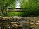 Picturesque covered bridge over a flowing river surrounded by green forest at 1075 Lancaster Sq, Roswell, GA 30076