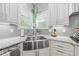 Kitchen with white cabinets, granite countertops, stainless steel sink, and sleek gray backsplash at 3111 Old Thompson Mill Rd, Buford, GA 30519