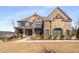 Beautiful brick and stone home with a covered front porch and manicured lawn at 13425 Bishops Ct, Roswell, GA 30075