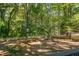 Expansive backyard with lush greenery, mature trees, white fencing and outdoor seating area with fire pit at 2010 Smith Nw Dr, Kennesaw, GA 30144