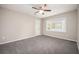 Neutral bedroom featuring plush gray carpeting, a lighted ceiling fan, and a bright window at 5474 Post Road Pass, Stone Mountain, GA 30088