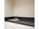 Wet bar featuring a stainless steel sink, black countertops and white cabinets at 5474 Post Road Pass, Stone Mountain, GA 30088