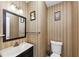 Cozy powder room features a modern vanity, mirror, and patterned wallpaper at 5705 Mountain Cres, Stone Mountain, GA 30087