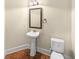 Powder room featuring a pedestal sink, framed mirror, and modern lighting fixture at 2100 Trinity Mill Dr, Dacula, GA 30019