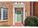 Close-up of a townhouse green front door with decorative trim and a red brick path at 3454 Ashwood Ln, Atlanta, GA 30341