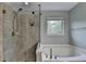 Bathroom featuring separate shower and bathtub, with tiled shower and window at 6845 Rocking Horse Ln, Cumming, GA 30040