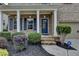 Inviting front entrance of a brick home with manicured bushes and a blue door at 6845 Rocking Horse Ln, Cumming, GA 30040