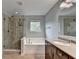 Main bathroom boasting a soaking tub, tiled shower, and granite counters at 6845 Rocking Horse Ln, Cumming, GA 30040