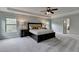 Large main bedroom featuring a ceiling fan, tray ceiling, carpet, and neutral paint at 6845 Rocking Horse Ln, Cumming, GA 30040
