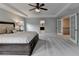 Main bedroom with neutral paint, carpet, ceiling fan, tray ceiling, and adjoining rooms at 6845 Rocking Horse Ln, Cumming, GA 30040