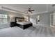 Spacious main bedroom with neutral paint, a tray ceiling, ceiling fan, and adjoining bathroom at 6845 Rocking Horse Ln, Cumming, GA 30040