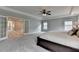 Large main bedroom with neutral paint, open doors, tray ceiling, and ceiling fan at 6845 Rocking Horse Ln, Cumming, GA 30040