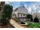 Exterior elevation of the rear of this two-story tan home featuring a stone water feature, garage and rear deck at 150 Karina Pl, Canton, GA 30115
