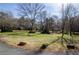 Wide front yard view showcasing a large lawn, mature trees, and the home's position within a serene setting at 150 Karina Pl, Canton, GA 30115