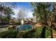 Outdoor pool area with mature landscaping, security fence, and access to a home's deck and backyard area at 150 Karina Pl, Canton, GA 30115