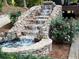 Beautiful stone waterfall surrounded by lush greenery and colorful flowers, a serene outdoor feature at 150 Karina Pl, Canton, GA 30115
