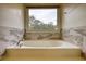 Elegant bathroom featuring a soaking tub with marble surround and large view window at 5770 Wyndemere Ln, Stone Mountain, GA 30087