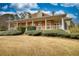 Attractive brick home with a sprawling front porch, manicured greenery, and a clear view of the sky at 5770 Wyndemere Ln, Stone Mountain, GA 30087