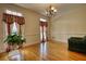 Bright living room featuring hardwood floors, large windows with decorative curtains, and a classic chandelier at 5770 Wyndemere Ln, Stone Mountain, GA 30087