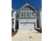 New construction two-story townhome showcases a 2-car garage, gray siding, and freshly painted white brick at 1587 Aiden Way # 43, Conyers, GA 30013